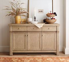 a wooden buffet table topped with fruit and veggies next to a framed mirror