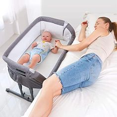 a woman laying on top of a bed next to a baby in a crib