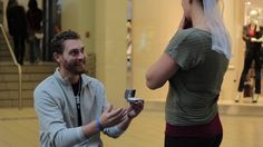 a man standing next to a woman in a mall holding a cell phone up to her ear