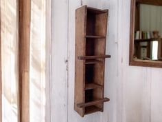 a wooden shelf hanging on the wall next to a mirror