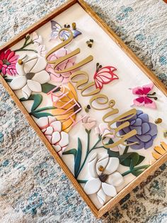 a wooden sign with flowers and butterflies on it