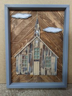 a wooden frame with a church and clouds on it