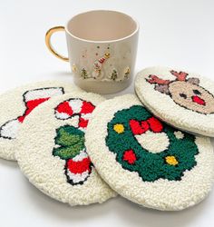 four coasters with christmas designs and a coffee cup