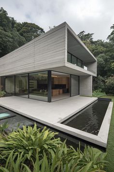 the house is made out of concrete and has a large pool in front of it