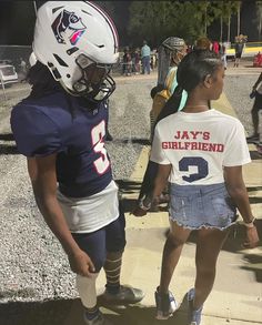 two girls in football uniforms are walking down the street