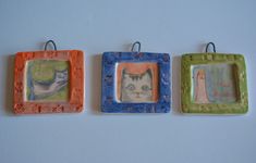 three small square ceramic ornaments with cats on them