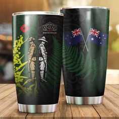 two travel mugs sitting on top of a wooden table next to an australian flag