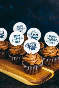 chocolate cupcakes with happy father's day stickers on them sitting on a cutting board