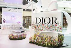 the interior of a retail store with flowers on display and an advertisement for dior