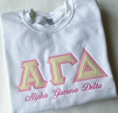 a white t - shirt with the letters aca and delta written on it in pink