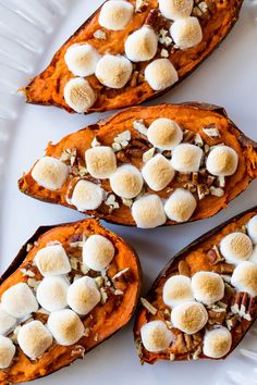 four sweet potatoes topped with marshmallows on a white plate