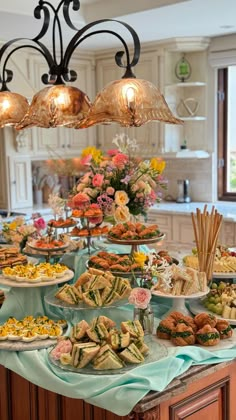 a table filled with lots of food on top of a kitchen counter next to a chandelier