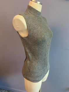 Vintage 1970's grey Acrylic stretch knit sleeveless turtleneck sweater made by Whistler's . Size Large, 40 1/2" bust, 25" length. Unworn deadstock in excellent condition with original tags! Grey Sleeveless Turtleneck Outfit, Gray Fitted High Neck Tops, Fitted Gray High Neck Tops, Fitted High Neck Gray Tops, Fitted Sleeveless Gray Sweater Vest, Fitted Sleeveless Fall Sweater, Fitted Gray Ribbed Knit Top, Fitted Ribbed Gray Knit Top, Fitted Gray Turtleneck Sweater