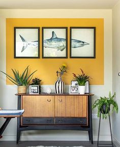 a living room with yellow walls and pictures on the wall