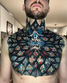 a man with tattoos on his chest is looking up at the camera while wearing an elaborate neck piece