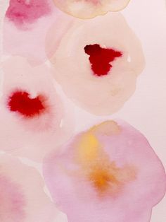 some pink and yellow flowers on a white surface with watercolor paint in it's center