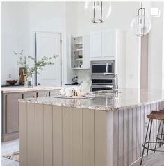 a kitchen with an island and two stools in front of the countertop area