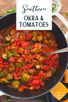 a pan filled with okra and tomatoes on top of a wooden table next to crackers