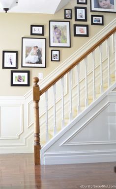 a staircase with pictures on the wall and wooden banisters in front of it