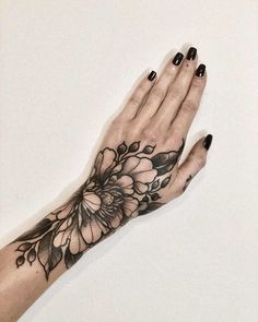 a woman's hand with black and white flowers on the left side of her arm