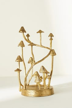 a gold sculpture with mushrooms growing out of it's sides on a white surface