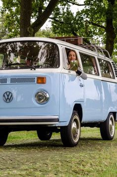 a woman sitting in the driver's seat of an old blue vw bus