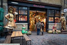 people are standing outside of a store with statues