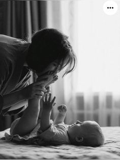 a woman is playing with her baby on the bed