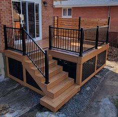 a wooden deck with metal railings next to a brick building