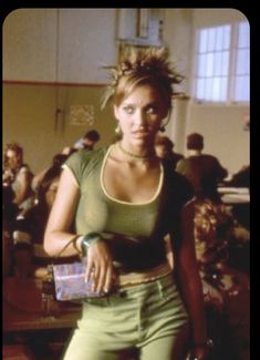 a woman standing in front of a group of people wearing green pants and crop tops