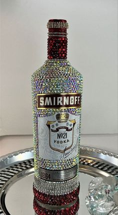 a bottle of smirnobff is sitting on a tray with some crystal beads