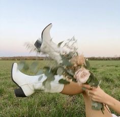 a woman laying on the ground with flowers in her hand and wearing white booties