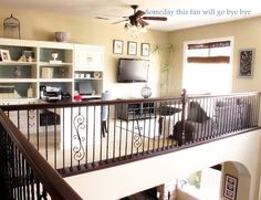 a living room filled with furniture and a flat screen tv on top of a wooden banister