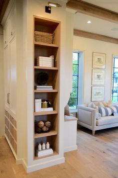 a living room filled with furniture next to a window covered in blinds and pillows on top of hard wood flooring