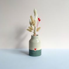 a vase with some flowers in it on a blue table top next to a white wall