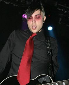 a young man in black shirt and red tie playing guitar