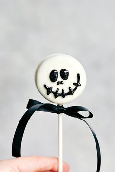 a hand holding a lollipop with a creepy face on it