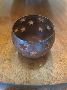 a metal bowl with stars on it sitting on a wooden table next to other items