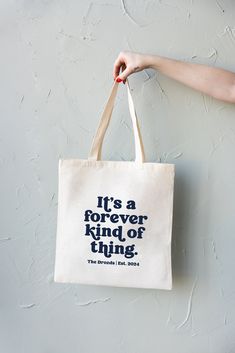 a person holding a tote bag that says it's a forever kind of thing