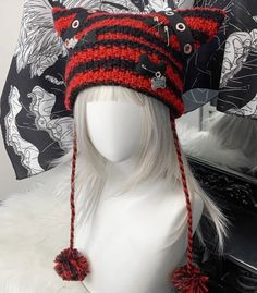 a white mannequin head wearing a red and black knitted hat with pom poms