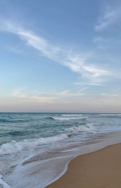 the ocean waves are rolling in and out on the shore line, with blue skies above