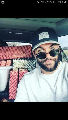 a man wearing sunglasses and a hat is sitting in the back seat of a car