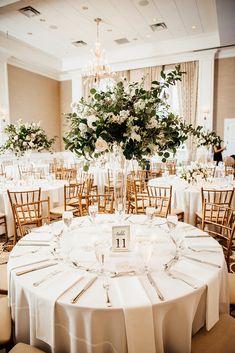 the tables are set up with white linens and centerpieces for an elegant wedding reception