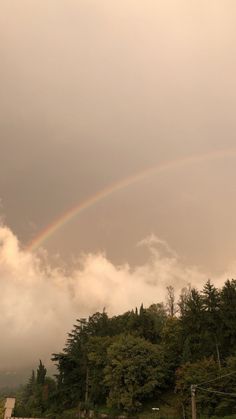 a rainbow in the sky over some trees