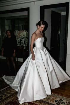 a woman in a white dress walking across a room