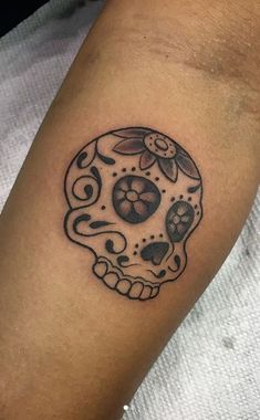 a black and white skull tattoo on the arm