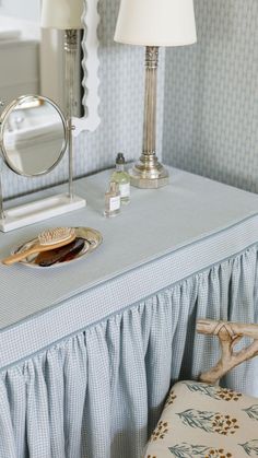 a table with a mirror, lamp and other items sitting on it in a room