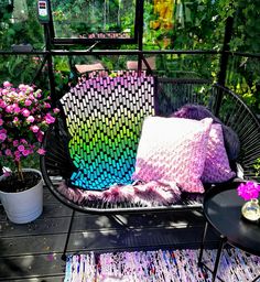 a chair with two pillows on top of it next to some flowers and potted plants