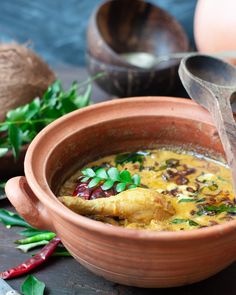 a clay bowl filled with soup and garnished with herbs