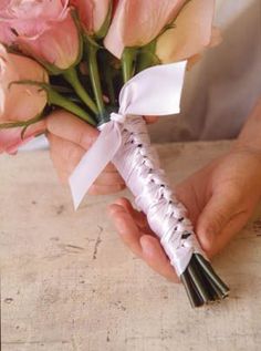 a person holding a bouquet of flowers in their hand with ribbons on it's end